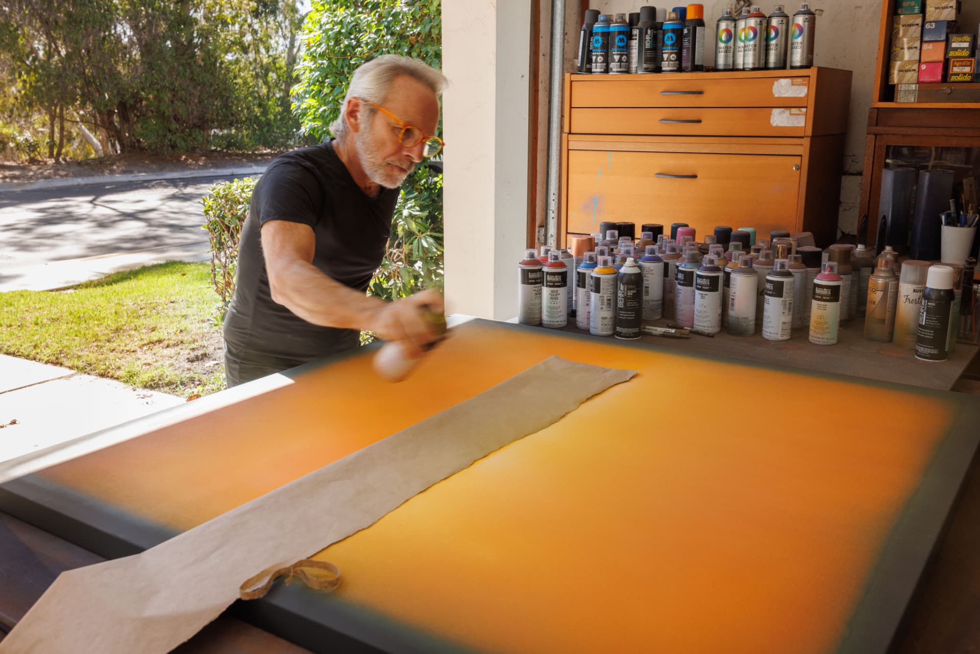 Jorge Engel applying color to an orange painting in his studio